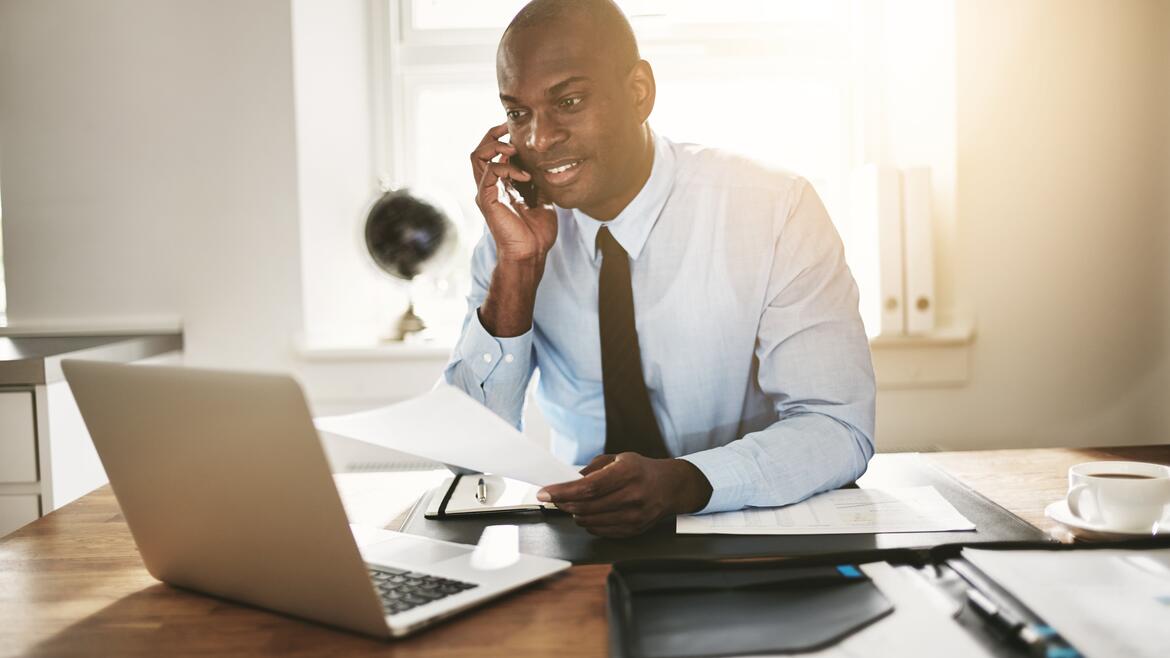 A man talking on the phone looking at the computer
